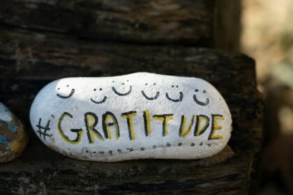 a white and yellow rounded stone with the word Gratitude on it