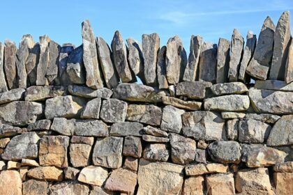 A rustic stone wall against a clear blue sky